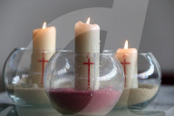 Three church candles in sand.