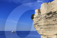 Old citadel atop cliffs with cruise ship anchored off shore, Bonifacio, Corsica, France