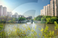 Stone bridge with pagoda style roofing, flanked by old style apartment buildings on the left and newer ones on the right.