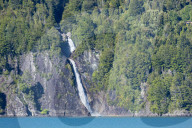 Patagonia - a boat in front of a waterfall on Puelo lake in the Tagua Tagua reserve