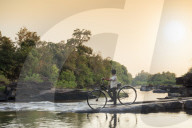School boy on a bicycle crossing a river on his way to school