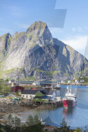 Ship in the blue sea frames the fishing village and the rocky peaks, Reine, Moskenesoya, Lofoten Islands, Norway, Scandinavia, Europe