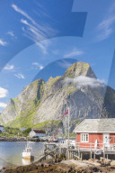 Typical house of fishermen called Rorbu framed by rocky peaks and blue sea, Reine, Moskenesoya, Lofoten Islands, Norway, Scandinavia, Europe