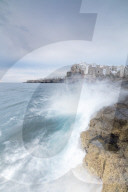 Waves of turquoise sea crashing on cliffs framed by the old town Polignano a Mare province of Bari Apulia Italy Europe