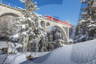 The red train on viaduct surrounded by snowy woods Cinuos Chel Canton of GraubÃ¼nden Engadine Switzerland Europe