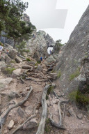 Hikers proceed in the rocky canyon Col de Bavella (Pass of Bavella) Solenzara Southern Corsica France Europe