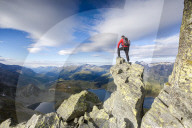 Hiker on top of rocks admires the blue Lake Montespluga in summer Chiavenna Valley Valtellina Lombardy Italy Europe