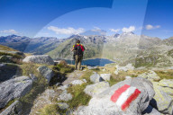 Hiker admires the blue Lake Montespluga and the rocky peaks in summer Chiavenna Valley Valtellina Lombardy Italy Europe