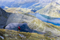 Hiker on the shore of Lago Nero admires the blue Lake Montespluga in summer Chiavenna Valley Valtellina Lombardy Italy Europe