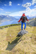 Hiker on green meadows admires Lake Como surrounded by woods Montemezzo Alpe Zocca Lombardy Italy Europe