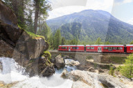 Bernina Express train surrounded by the alpine creek, Morteratsch, canton of GraubÃ¼nden, Engadin Valley, Switzerland, Europe