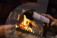Bottle and glass of wine in front of fireplace, San Romerio Alp, Brusio, Canton of GraubÃ¼nden, Poschiavo valley, Switzerland
