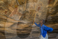 Guide pointing at cave paintings in Lass Geel caves, Somaliland, Somalia