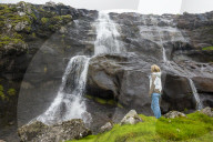 Woman looking at a waterfall in Estuyroy, Faroe islands, Denmark