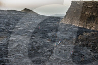 Tourists walking through lava field around the very active Erta Ale shield volcano, Danakil depression, Ethiopia