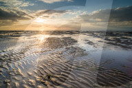 View of sandy beach and pools at low tide, at sunset, Reculver, Kent, England