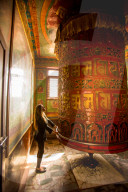Woman praying at a Buddhist prayer wheel in Bouddha temple