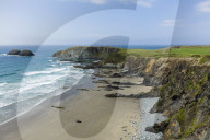 A beach along the Pembrokeshire coast national park with the coastal path running along the cliff tops above.