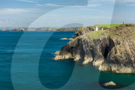 A solitary walker perched high on the cliffs stretching for miles along the Pembrokeshire coast path on a calm summers day.