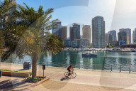 A lone cyclist rides along the waterfront, Dubai Marina, Dubai, UAE.