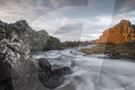 A river flows from the Ã–xarÃ¡rfoss waterfall during sunrise in Thingvellir National Park, Iceland.