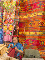 Woman sewing in market with background of handmade rugs, Oaxaca, Mexico, North America