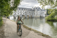 Girl cycling with Chenonceau castle on the background. Chenonceaux, Indre-et-Loire, France.