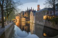 Houses and bridge reflection on Groenerei canal at dusk. Bruges, West Flanders province, Flemish region, Belgium.