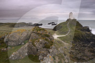 Under a pink, cloudy sky sits the lighthouse at the edge of Llanddwyn Island, Anglesey, Wales.