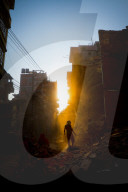 In rays of early evening sun on the dusty streets of Thamel, Kathmandu, Nepal, a family begins to clear the debris of where thei