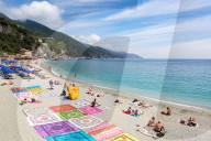 Blanket sellers showcasing their products on the beach at Monterosso, Cinque Terre, Liguria, Italy