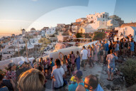Behind the scenes of a famous Oia sunset on the Greek island of Santorini. People line every part the town's walls.