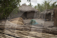 A traditional mud hut home with a thatched roof has a solar panel on the top of it.