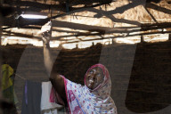 A woman smiling as she turns on the new solar light in her mud hut.