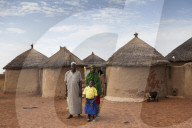 A young school girl with her parents outside their home in Tinguri, northern Ghana.