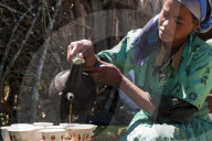 A woman pouring coffee from a traditional Ethiopian coffee pot.