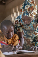 A teacher helping a young student at a school on Ghana