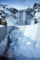 Winter view of Skogafoss waterfall, with cliffs covered in Icicles and foregreound covered in snow, Skogar, South Iceland