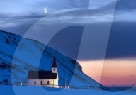 Floodlit church at dawn against snow covered mountains, winter, near Vik, South Iceland