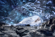 View from inside ice cave under the Vatnajokull Glacier towards snow covered mountains, near Jokulsarlon Lagoon, South Iceland