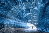 View from inside ice cave under the Vatnajokull Glacier with person for scale, near Jokulsarlon Lagoon, South Iceland