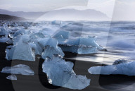 Glacial icebergs washed up from North Atlantic Ocean onto volcanic sand beach near Jokulsarlon, South Iceland