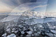 Frozen Jokulsarlon Glacial Lagoon in winter with ice in the foreground and snow covered distant mountains, South Iceland