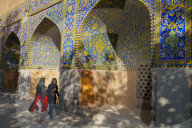 Two Iranian girls walking past courtyard walls, Imam Mosque, Isfahan, Iran
