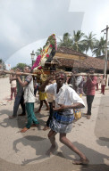 Men dancing to drumbeat as bronze deity covered with puja mala (garlands) being carried along the street, Tranquebar, Tamil Nadu