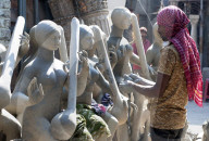 Sculptor adding hands to goddess Durga deities, made of Hooghly river clay over straw base in Kumartuli potters quarter, Kolkata
