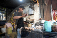 Chai wallah, pouring Indian chai into traditional hand made terra cotta clay cups, in chai stall outside Kali temple, Kolkata