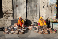 Two women in yellow and orange saris, selling hand made decorated terra cotta pots and bowls, Diggi village, Rajasthan