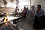 Naga men sitting chatting round fire in village muting (meeting hall), Nagaland