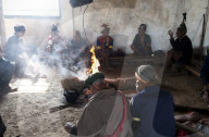 Naga men sitting chatting around the central fire in their village murung (village hall), Hongphui village, Nagaland